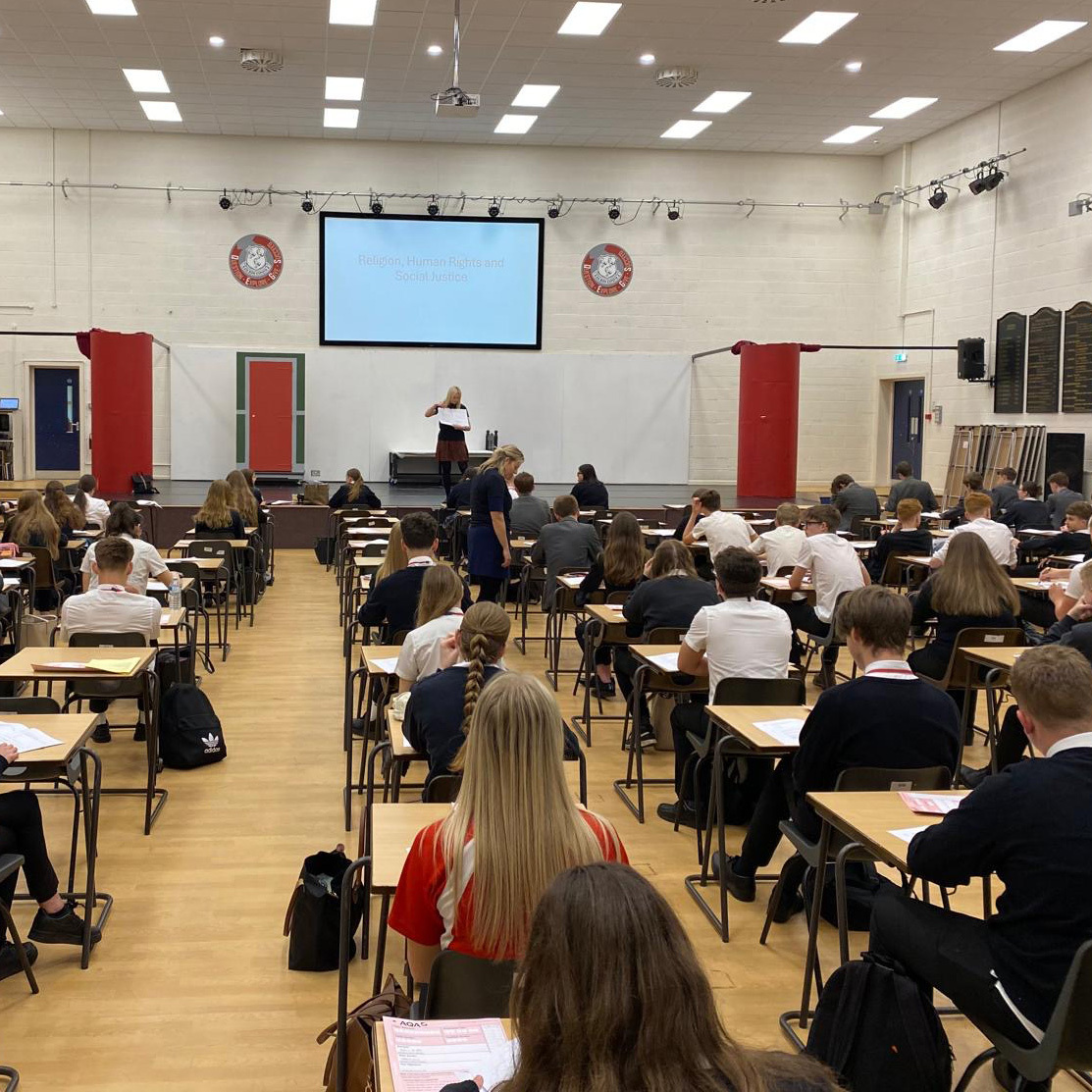 A group of students in a school hall revising for their RS exam.